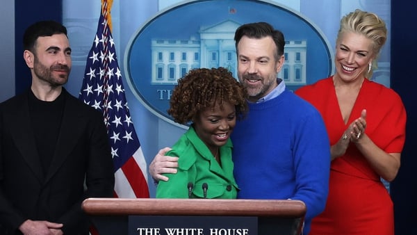 Ted Lasso star Jason Sudeikis embraces White House Press Secretary Karine Jean-Pierre as other cast members Brett Goldstein (L) and Hannah Waddingham look on during a White House daily news briefing on Monday