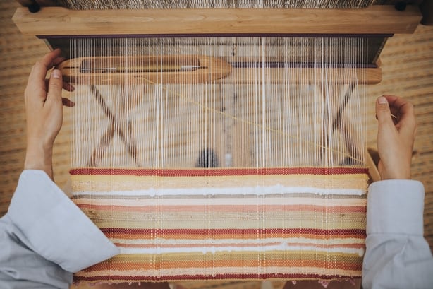 White lands working on a loom