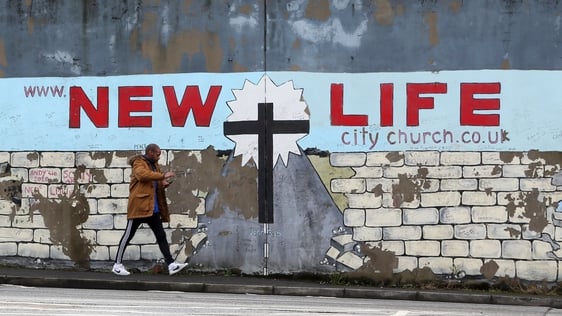 A man walks past a section of The Peace wall between the Falls Road and the Shankill road in Belfast, 2017. Photo credit: PAUL FAITH/AFP via Getty Images