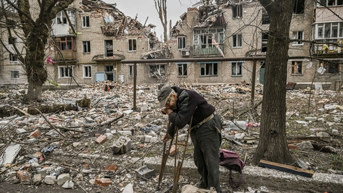 An elderly man collects wood from debris in front of a destroyed apartment building in Avdiivka earlier this month