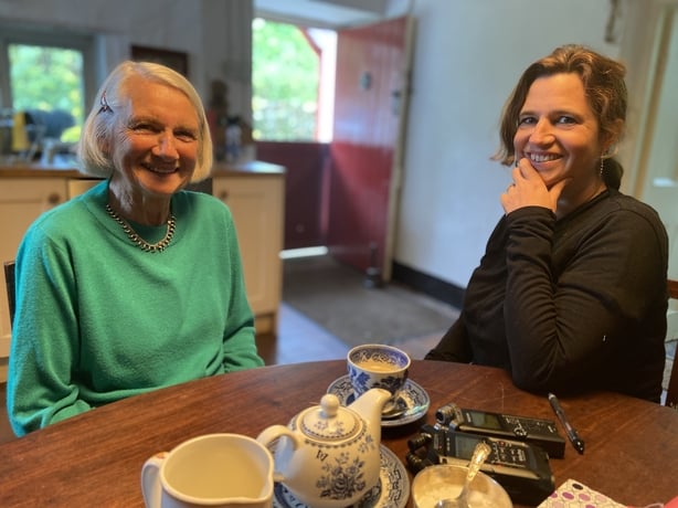 Two women, one with grey hair, sitting at a table.