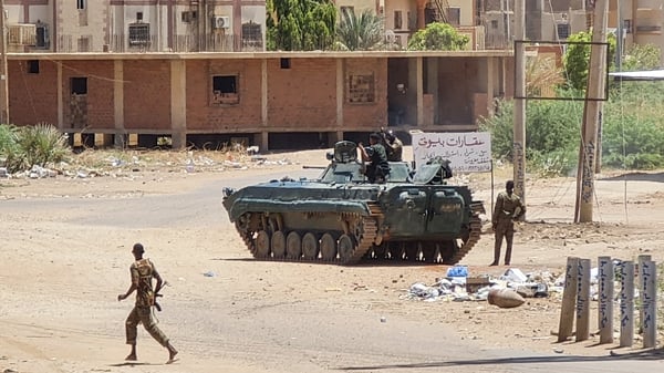 Sudanese Army soldiers walk near armoured vehicles stationed on a street in southern Khartoum