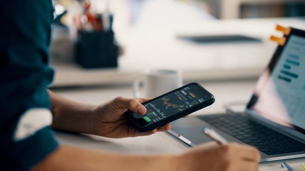 Mid adult man checking financial information on a smart phone while doing his bookkeeping