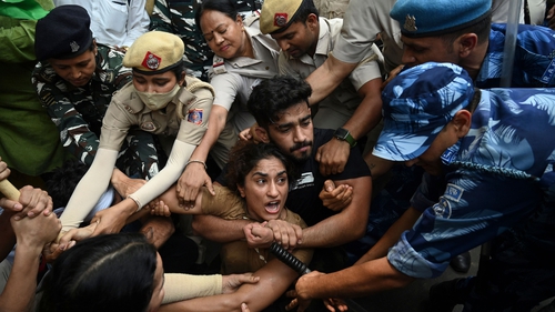 Indian wrestlers Vinesh Phogat (C) with others are detained by the police while attempting to march to India's new parliament