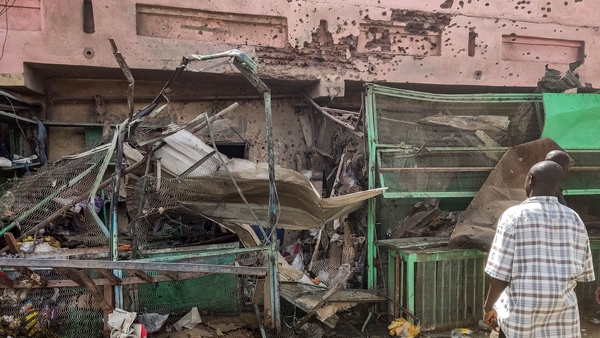 People walk past a medical centre building riddled with bullet holes in the south of Khartoum
