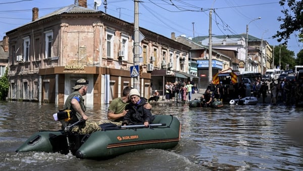 Officials help people to evacuate their homes after the explosion at the Kakhovka hydropower plant that flooded houses and streets in Kherson