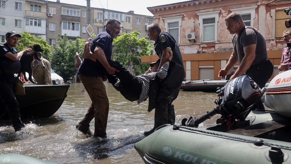 Ukrainian security forces carry an elderly resident to a boat during an evacuation from a flooded area in Kherson