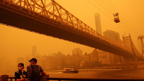 People wear protective masks as the Roosevelt Island Tram crosses the East River