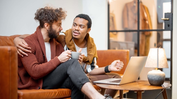 A gay male couple talking on the sofa 