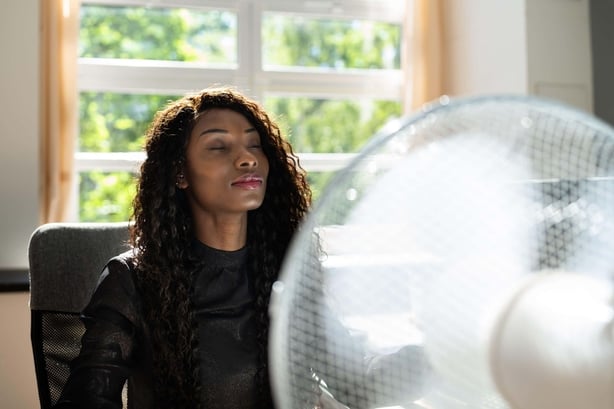 Woman sitting in front of a large desk fan