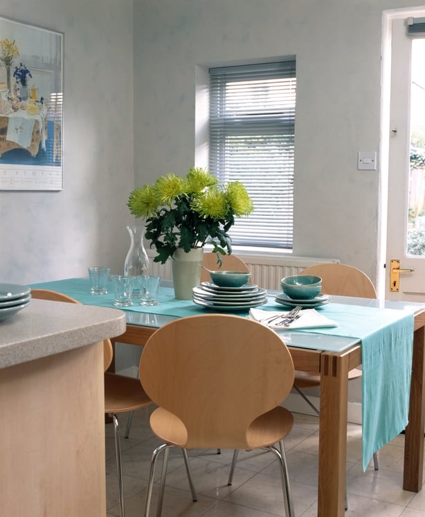Vase of lime green chrysanthemums on glass topped table in kitchen