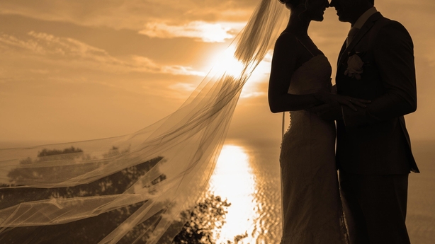 Silhouette of bride and groom kissing over sunset background