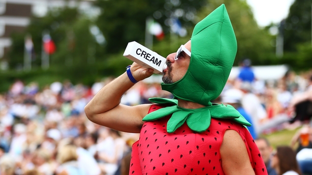 A man dressed as a strawberry drinks cream on Murray mound on day seven of the Wimbledon Lawn Tennis Championships