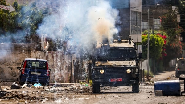 Israeli soldiers fire tear gas canisters from an armoured vehicle during a military operation in the occupied West Bank city of Jenin