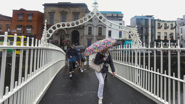 People in Dublin shelter from heavy rain as they cross the Ha'penny Bridge (Pic: RollingNews.ie)