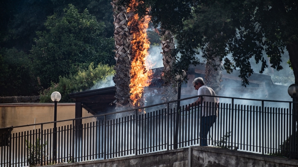 A man desperately tries to extinguish flames in the Aci Catena area 20km from Catania in Sicily