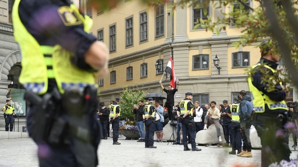 Police officers stand next to demonstrators at Mynttorget square in Stockholm, Sweden
