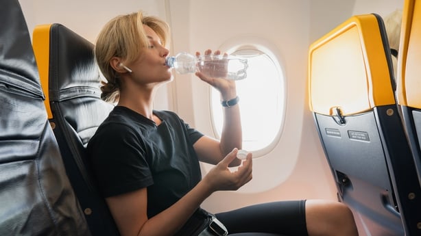 Woman drinks water during her flight in an airplane