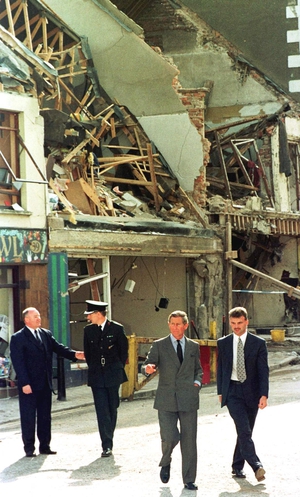 Three days after the blast, Britain's then-Prince Charles, walks past shops destroyed by the bomb