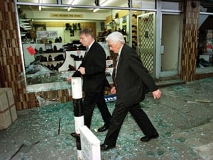That same day, Deputy First Minster Seamus Mallon walks though broken glass to see the carnage after the explosion