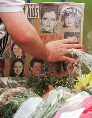 As a new week begins on Monday 17 August, a man touches a photograph of one of the victims, on a homemade card left at the bomb site. Floral tributes continue to pour in.