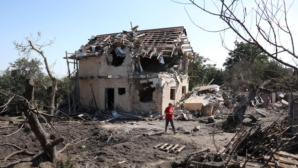A local resident walks past a crater and a destroyed residential house following a missile strike in the Kyiv region yesterday