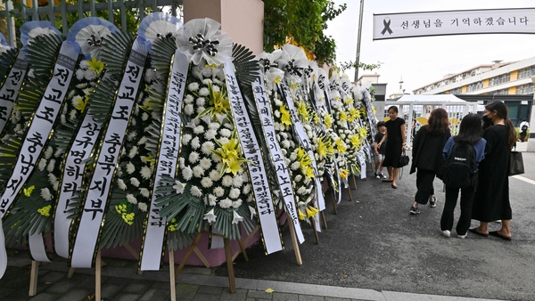 Mourners walk past funeral wreaths in front of the main gate of Seoul Seoi Elementary School