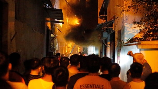 Bystanders look on as the fire engulfs the building in Hanoi