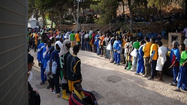 Migrants queue at a camp in the harbour of the Italian island of Lampedusa yesterday