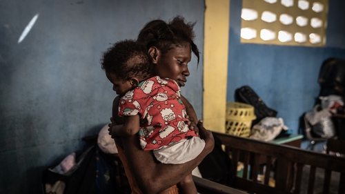 A young displaced Haitian mother holds her child inside a former church hall in downtown Port-au-Prince on September 12, 2023