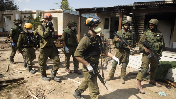 Israeli soldiers tour the Kfar Aza kibbutz searching for more victims