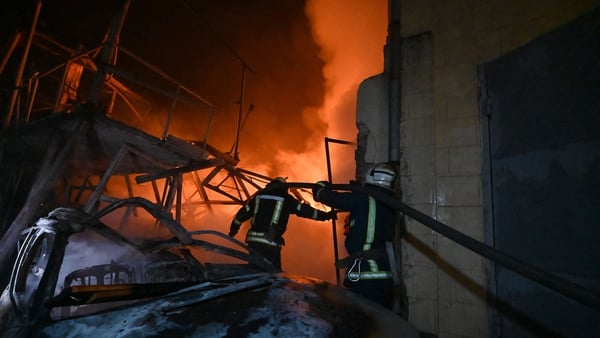 Ukrainian firefighters work to extinguish a fire following an overnight Russian drone strike in Kharkiv