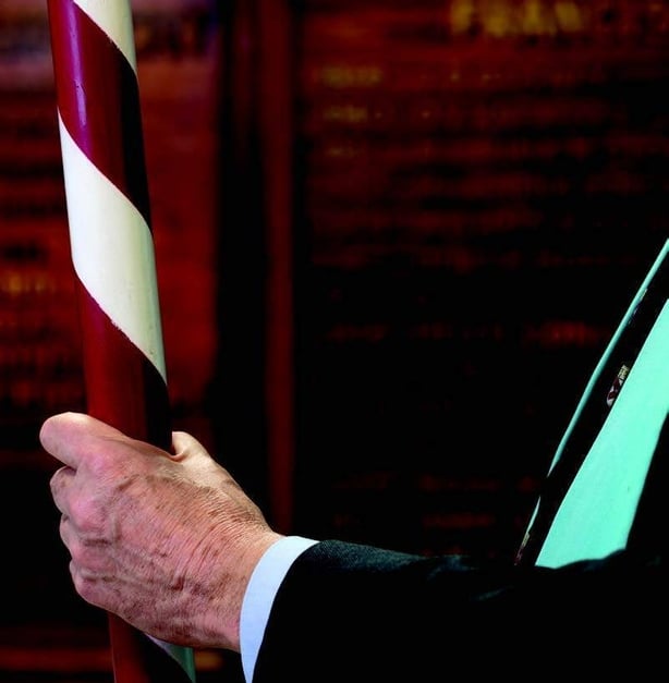 Man's hand holding a red and white stripped pole