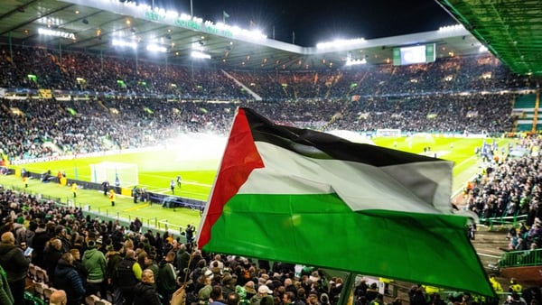 A Celtic supporter waves a Palestine flag ahead of the clash against Atletico Madrid