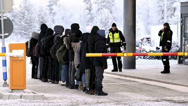 Migrants stand in a line in front of border guards at the international border crossing at Salla in northern Finland