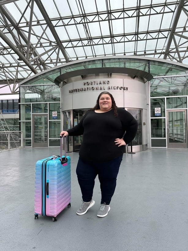 A woman in front of the entrance to Portland International Airport