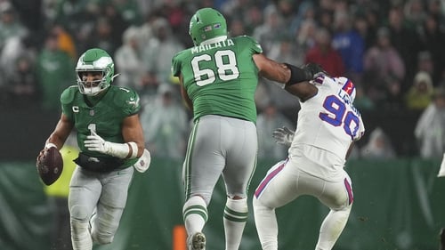 Jalen Hurts (L) of the Philadelphia Eagles runs with the ball as Jordan Mailata blocks Shaq Lawson