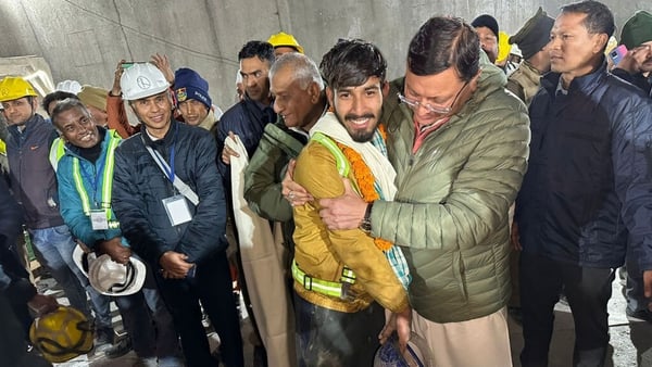 Uttarakhand chief minister Pushkar Singh Dhami, centre, with a rescued worker inside the tunnel