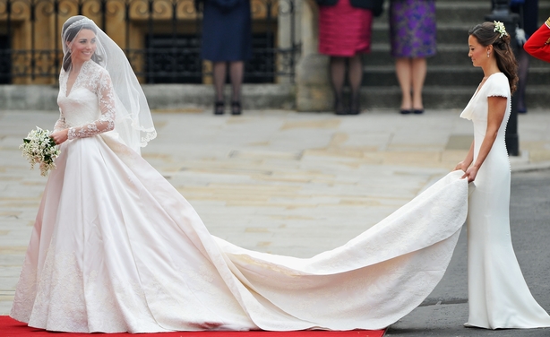 Catherine Middleton waves to the crowds as her sister and Maid of Honour Pippa Middleton holds her dress before walking in to the Abbey to attend the Royal Wedding of Prince William