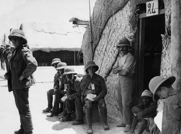 A black and white photo of soldiers waiting outside a hospital hut