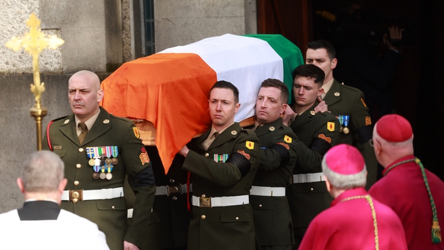 John Bruton's coffin, draped in the tricolour, is carried from the church