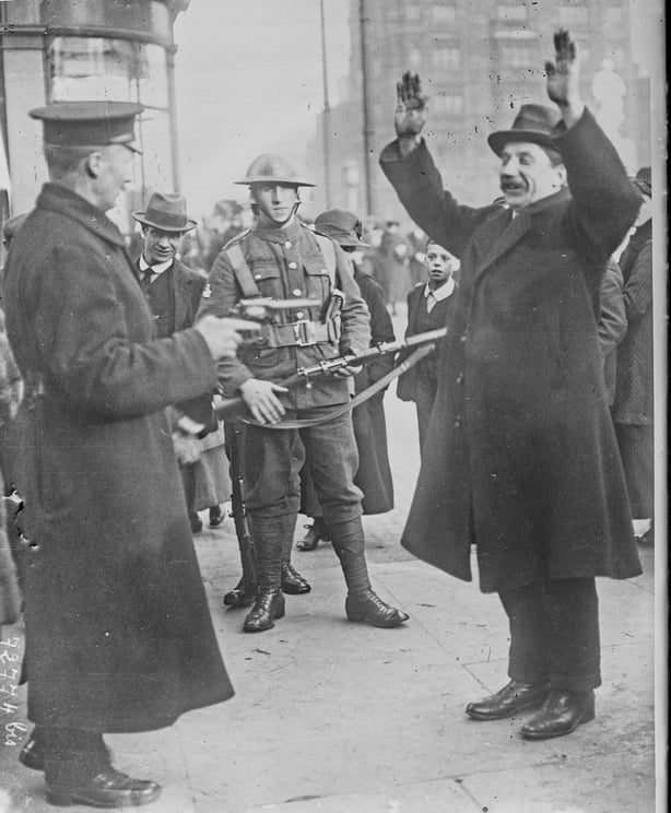 Soldier pointing a gun at a middle aged man in a suit