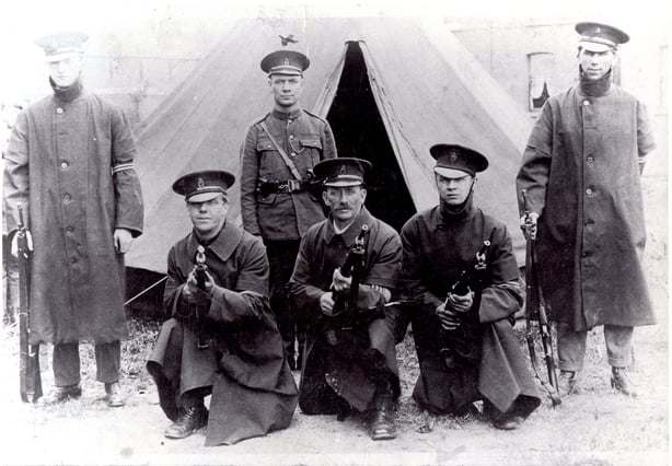 Black and white photo of a small group of uniformed white men in 1920s uniforms  holding guns