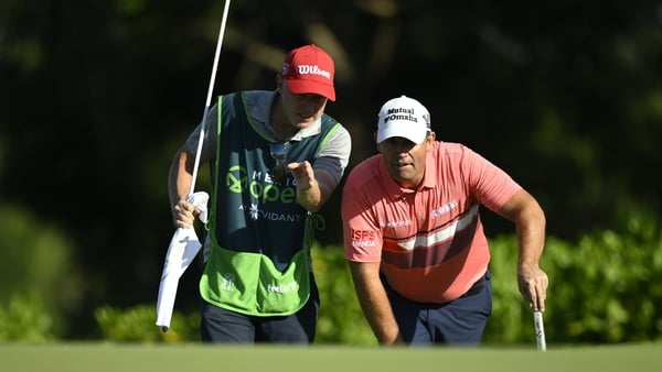 Harrington lining up a putt alongside his caddie on the third green during the third round