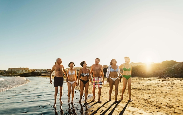 2R46TNW Happy multiracial senior friends having fun walking on the beach at sunset during summer holidays - Diverse elderly people enjoying vacations