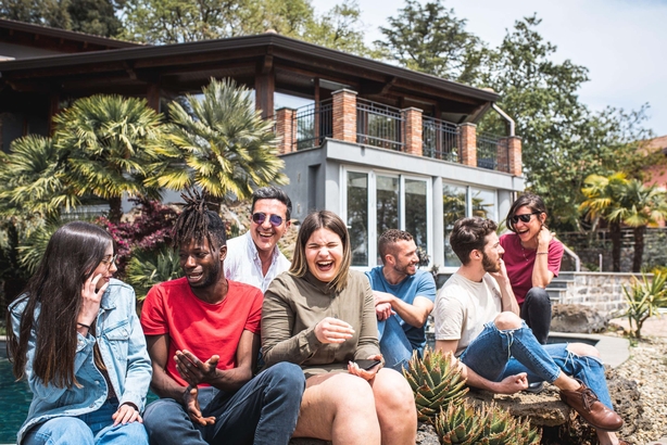 2M70WGX Happy multiracial friends on holiday in a luxury house standing at the poolside