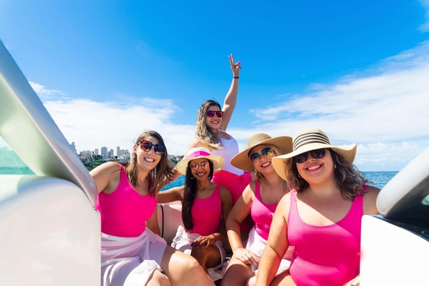 Female friends on top of a boat against the sea in the background. Salvador, Bahia, Brazil.