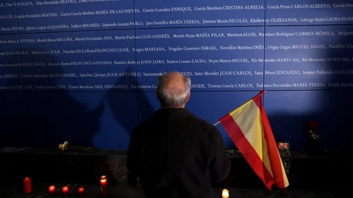 A man stands in front of a panel bearing names of the victims of the 11M attacks, which killed 192 people on 11 March 2004