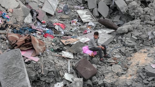 A boy sits among the rubble and scattered belongings of the al-Atrash family, after their home was destroyed in an Israeli strike in Deir el-Balah in central Gaza