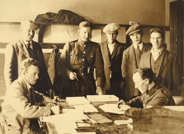 Young men stand around a table in a sepia photograph